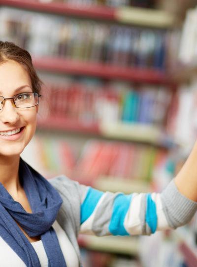 Female student selects a book in a library